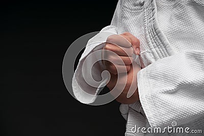 Hands closeup - teenager dressed in martial arts clothing posing on a dark gray background, a sports concept Stock Photo