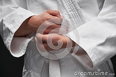 Hands closeup - teenager dressed in martial arts clothing posing on a dark gray background, a sports concept Stock Photo