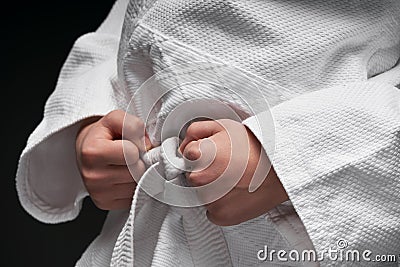 Hands closeup - teenager dressed in martial arts clothing posing on a dark gray background, a sports concept Stock Photo