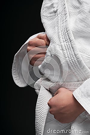 Hands closeup - teenager dressed in martial arts clothing posing on a dark gray background, a sports concept Stock Photo