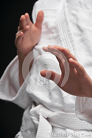 Hands closeup - teenager dressed in martial arts clothing posing on a dark gray background, a sports concept Stock Photo