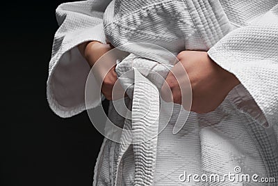 Hands closeup - teenager dressed in martial arts clothing posing on a dark gray background, a sports concept Stock Photo