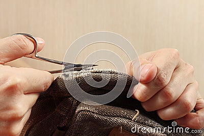 Hands of clothier with a pair of scissors cut strong cloth close up Stock Photo