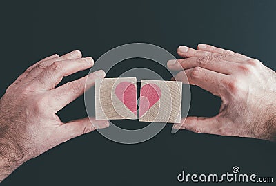 Hands connecting or disconnecting woodenblocks with red heart Stock Photo