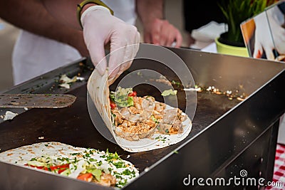 Hands of cook preparing fajita wrap with beef and vegetable salad. Mexican food. Party food. Stock Photo