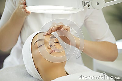 Hands of cosmetologist youching womans forehead and checking skin elasticity Stock Photo