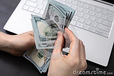 Hands counting money. Counting American dollars with hand near laptop. Income and Business concept Stock Photo
