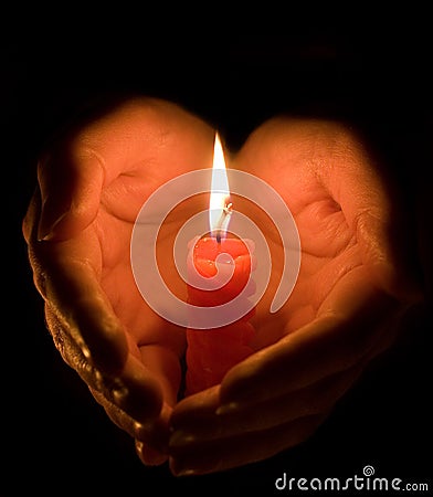 Hands cupped around a candle Stock Photo