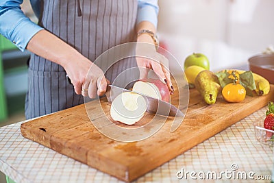 Hands cutting an apple on chopping board. Young woman preparing a fruit salad in her kitchen Stock Photo