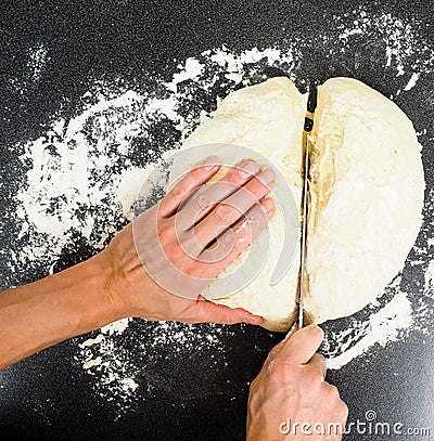 Hands cutting a lump of dough with knife Stock Photo