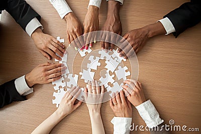 Hands of diverse people connecting puzzle together, top closeup Stock Photo
