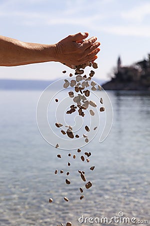 Hands dropping small stones in the sea Stock Photo