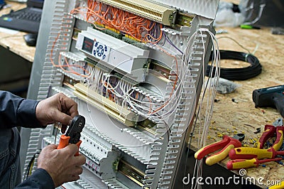 Hands of electrical technician assembling low voltage industrial HVAC control cubicle in workshop. Close-up photo. Stock Photo