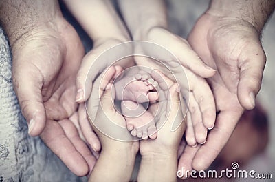 Hands of father, mother, daughter keep little feet baby. Friendly happy family Stock Photo