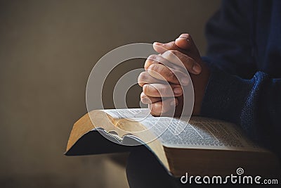 Hands folded in prayer on a Holy Bible in church concept for faith Stock Photo