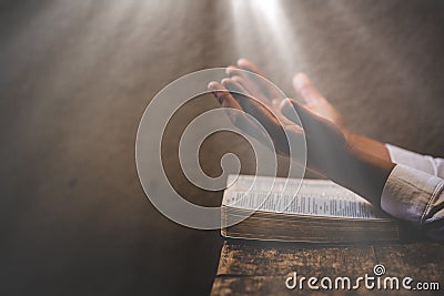Hands folded in prayer on a Holy Bible in church concept for faith Stock Photo