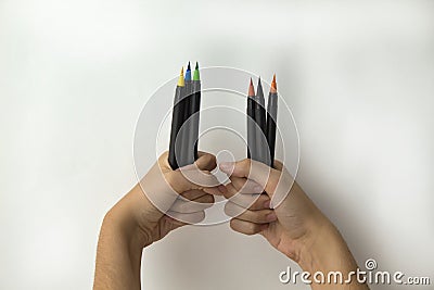 hands of a girl with a handful of color pens and markers on white background Stock Photo