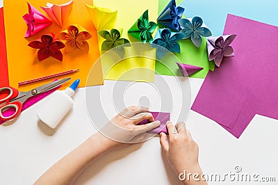 Hands of the girl origami puts flowers from paper of Violet trend color. Lesson of origami. Flat lay style Stock Photo