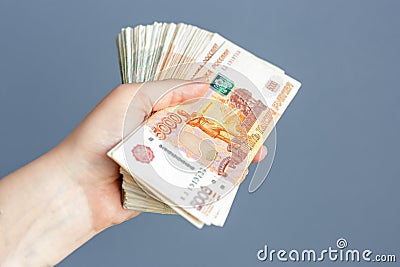 Russian, paper banknotes in their hands on a blue background. Space for text. Stock Photo