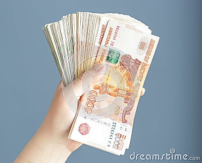 Russian, paper banknotes in their hands on a blue background. Stock Photo