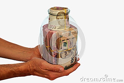 Hands with glass jar full of hryvnia banknotes, the money of Ukraine. Concept of money deposited in a savings bank account. Stock Photo