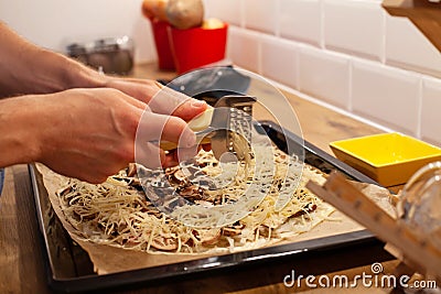Hands grating cheese on top of pizza or flammekueche Stock Photo