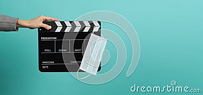 Hands with grey suit and hold black Clapper board or movie slate with face mask. it use in video production ,movies and cinema Stock Photo