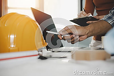 Hands of group engineer and architect working on laptop computer and blueprint on workplace desk Stock Photo