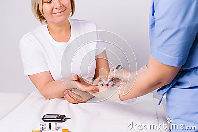 Hands of a healthcare professional using a glucometer to take an analysis from an older woman on a white background. Stock Photo