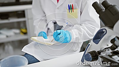 Hands of hispanic woman scientist taking notes at laboratory Stock Photo