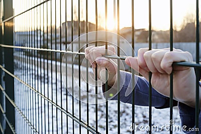 The hands hold onto the metal fence Stock Photo