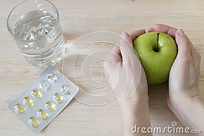 Hands holding apple. Medicine pills and a glass Stock Photo