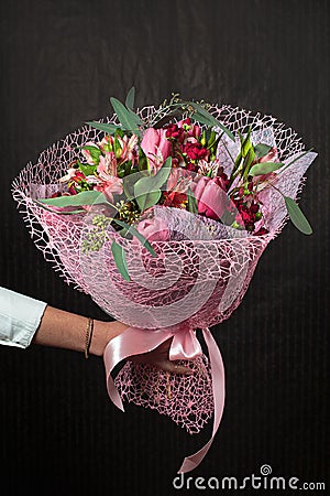 Florist holding a buquet of various flowers on the dark background Stock Photo