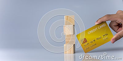 Hands holding credit cards and wooden cube blocks stacked on top of each other. Cashless spending concept Stock Photo