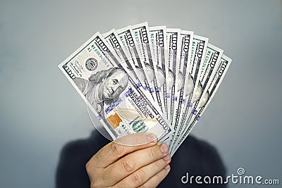 1000 dollars in 100 bills in a man`s hand close-up on a dark background. Hands holding dollar cash Stock Photo