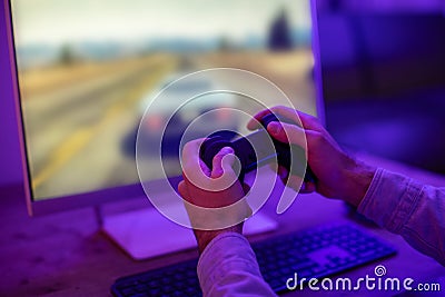 Hands holding a game controller before a screen Stock Photo