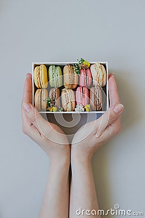 Hands holding gift box with delicious macaroons on the light blue background, top view Stock Photo