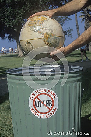 Hands holding a globe over a park trash receptacle Editorial Stock Photo