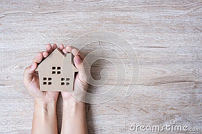 Hands holding house model on wood table background with copy space. Financial, money, refinance, Real estate and new home concept Stock Photo