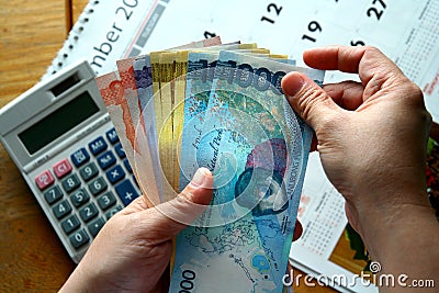 Hands holding Money Bills and a calculator and a calendar Stock Photo