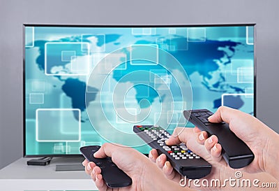 Hands holding multimedia remote control with smart TV Stock Photo