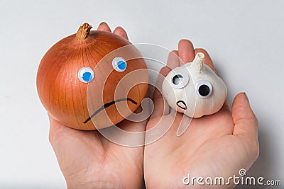 Hands holding onions and garlic on white background. Products characters with funny faces Stock Photo