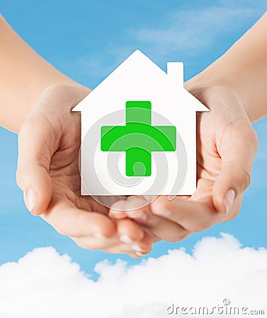 Hands holding paper house with green cross Stock Photo