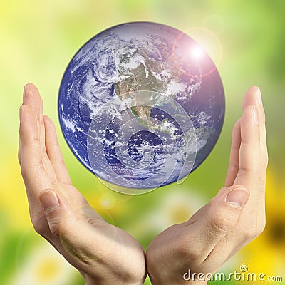 Hands holding the planet on blurred green bokeh background color of a natural tree with leaves, facing the sun-flared Stock Photo