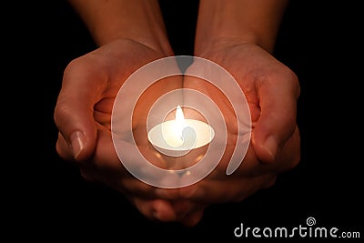 Hands holding and protecting lit or burning candle candlelight on darkness. Stock Photo