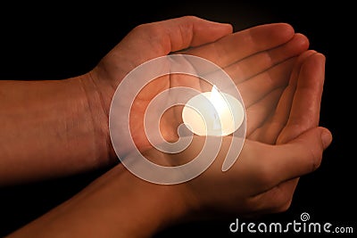 Hands holding and protecting lit or burning candle candlelight on darkness. Stock Photo