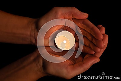 Hands holding and protecting lit or burning candle candlelight on darkness. Stock Photo