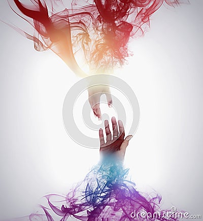 Hands holding or reaching for each other with colorful smoke Stock Photo