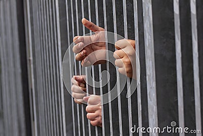 Hands holding and reaching out of strong iron bars. Prison or immigrant and refugee crisis. Dramatic border fence or concept Stock Photo