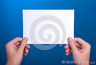 Hands holding white sheet paper card on blue Stock Photo